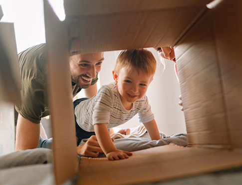 Young boy and parents playing with box in living room